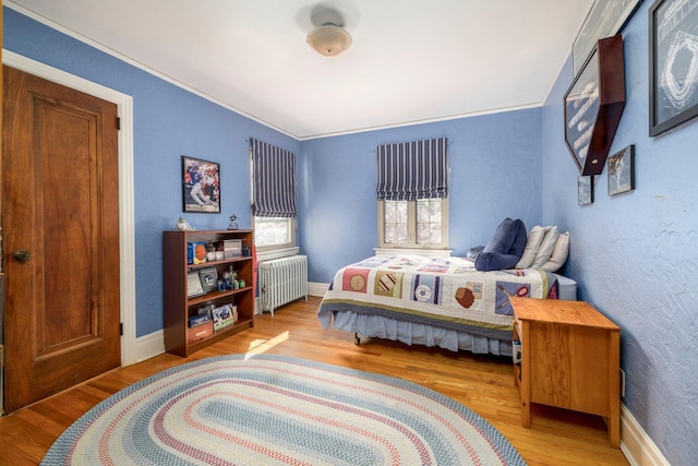 bedroom featuring baseboards, radiator heating unit, and wood finished floors