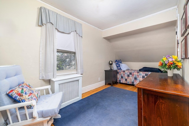 bedroom with baseboards, crown molding, and wood finished floors