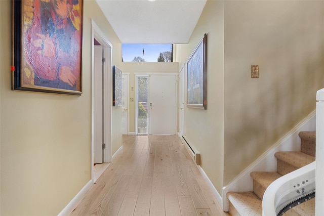 hallway with wood-type flooring, stairs, baseboard heating, and baseboards