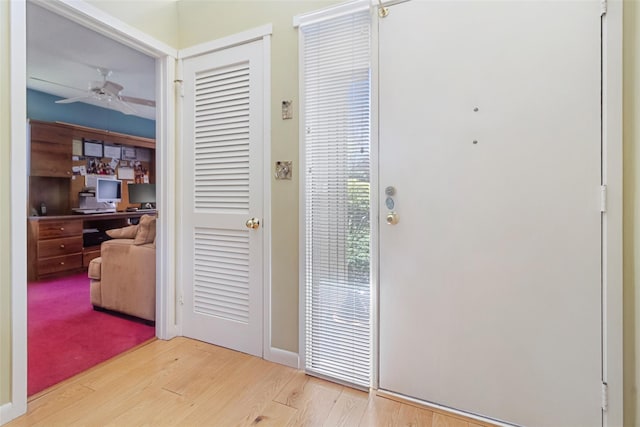 doorway with baseboards, wood finished floors, and ceiling fan