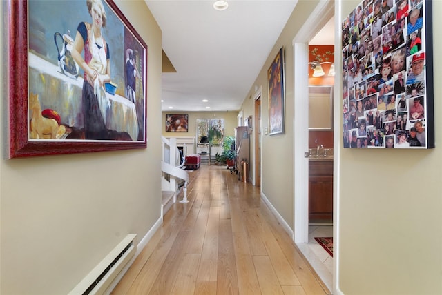 hallway with hardwood / wood-style flooring, a sink, baseboard heating, baseboards, and recessed lighting