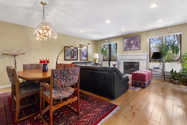 dining room featuring light wood-type flooring, recessed lighting, a notable chandelier, and a brick fireplace