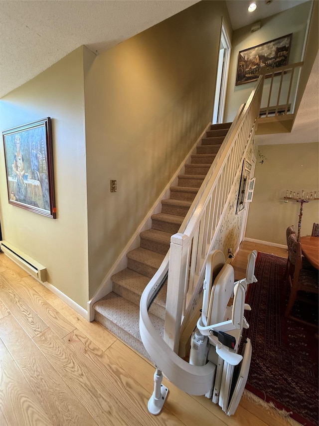 stairs featuring a baseboard heating unit, recessed lighting, wood finished floors, and baseboards