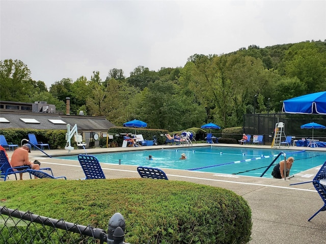 pool with fence, a patio, and a forest view