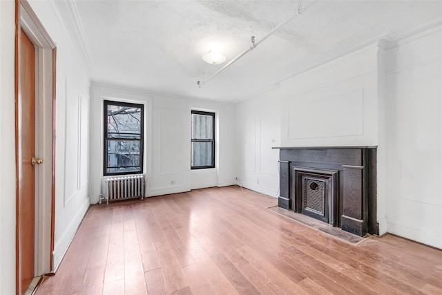 201 Madison St, Brooklyn, NY 11216 - unfurnished living room with crown molding, a fireplace with flush hearth, baseboards, radiator, and light wood-style flooring