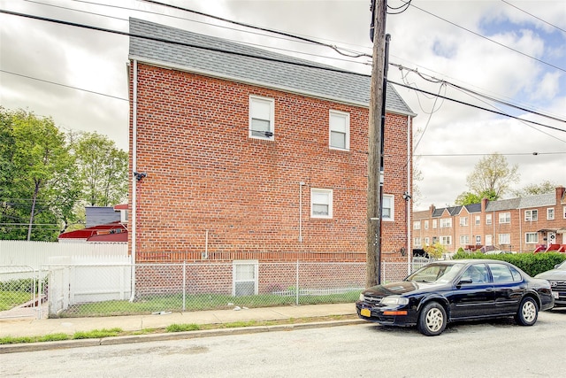 225-54 Murdock Ave, Queens Village, NY 11429 - view of home's exterior with brick siding, fence, and roof with shingles