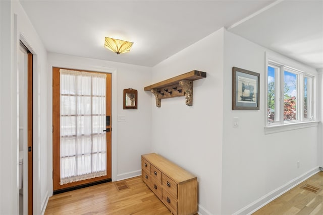 doorway with baseboards, light wood-style flooring, and visible vents