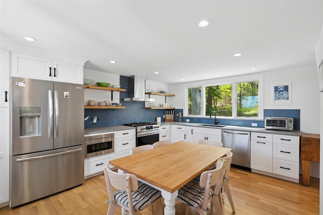 kitchen with backsplash, stainless steel appliances, open shelves, and wall chimney exhaust hood