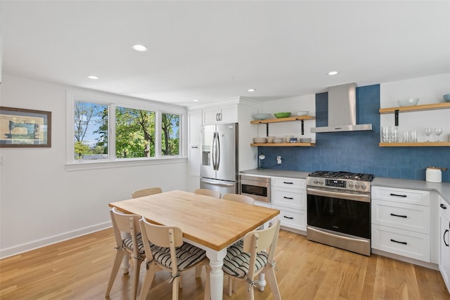 kitchen featuring wall chimney range hood, open shelves, appliances with stainless steel finishes, and decorative backsplash