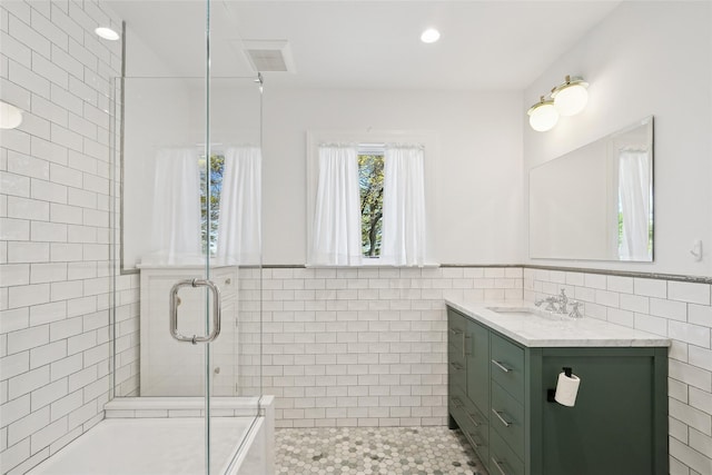 bathroom featuring vanity, tile patterned flooring, tile walls, a tub, and a tile shower