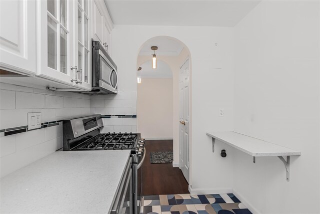 3333 Henry Hudson Pkwy Unit 7C, Bronx, NY 10463 - kitchen with white cabinetry, decorative backsplash, glass insert cabinets, stainless steel appliances, and arched walkways