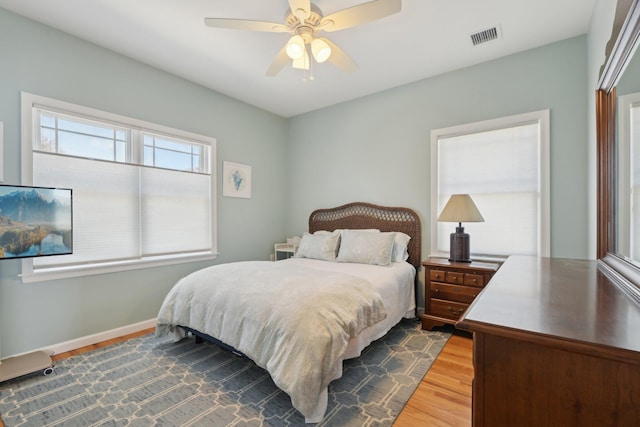 bedroom with a ceiling fan, baseboards, visible vents, and wood finished floors