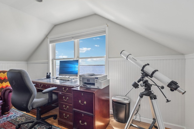 office space featuring light wood finished floors, wainscoting, and vaulted ceiling