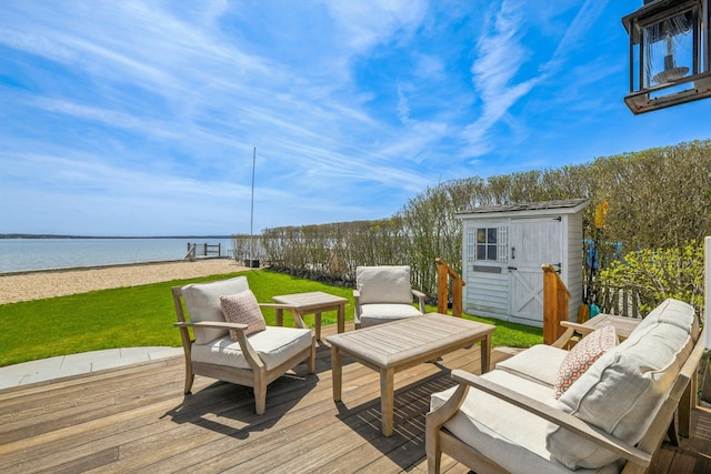 wooden deck with a storage unit, outdoor lounge area, a water view, a lawn, and an outdoor structure