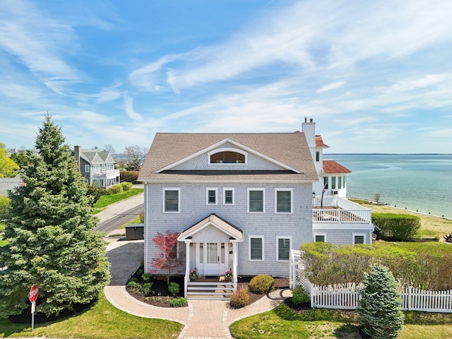 greek revival inspired property featuring fence, a water view, a chimney, and a balcony