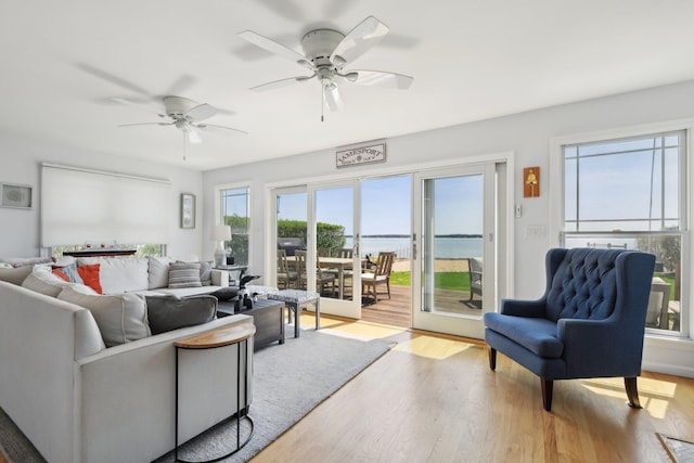 living room with a water view, ceiling fan, and wood finished floors