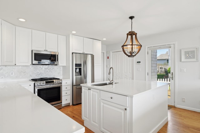 kitchen featuring backsplash, light wood-type flooring, a sink, light countertops, and stainless steel appliances