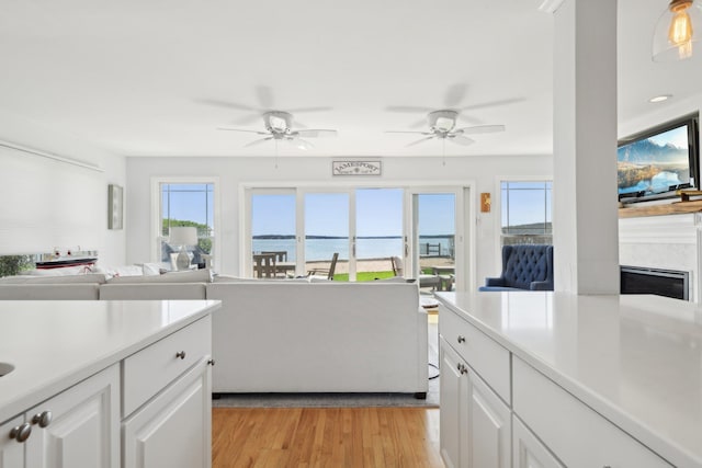 kitchen featuring light countertops, light wood finished floors, white cabinetry, and open floor plan