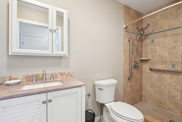 bathroom featuring vanity, a tile shower, and toilet
