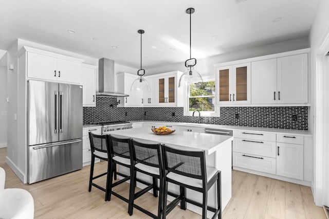 260 Wilmot Rd, Ocean Beach, NY 11770 - kitchen with glass insert cabinets, wall chimney range hood, high quality fridge, light countertops, and light wood finished floors