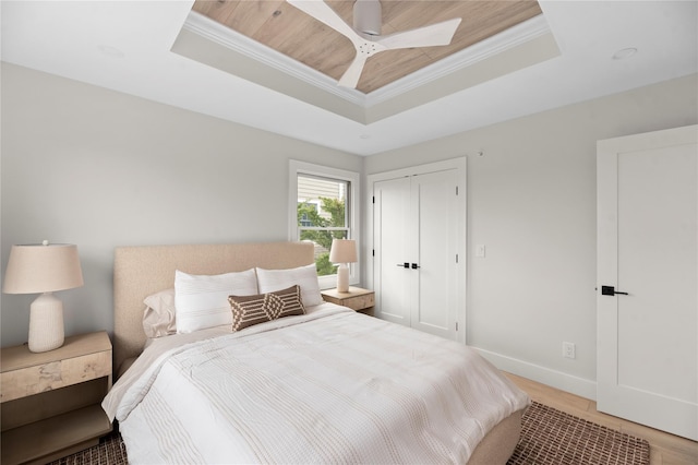 260 Wilmot Rd, Ocean Beach, NY 11770 - bedroom with crown molding, a closet, baseboards, a tray ceiling, and light wood-style flooring