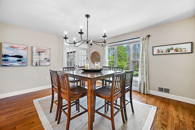 dining area featuring baseboards, a notable chandelier, wood finished floors, and visible vents