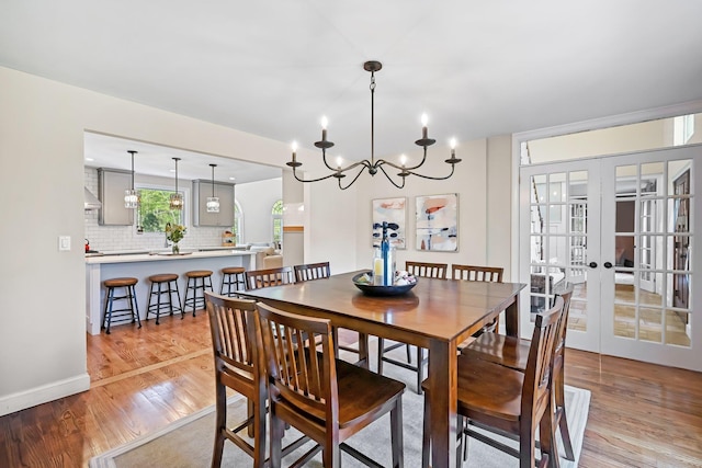 dining room featuring french doors, a notable chandelier, and light wood-style flooring
