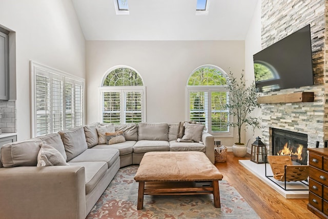 living area featuring light wood-style floors, high vaulted ceiling, and a fireplace