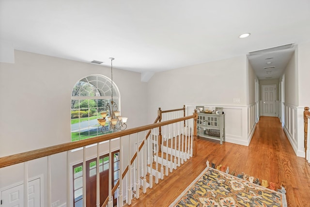 corridor with a notable chandelier, recessed lighting, an upstairs landing, wood finished floors, and visible vents