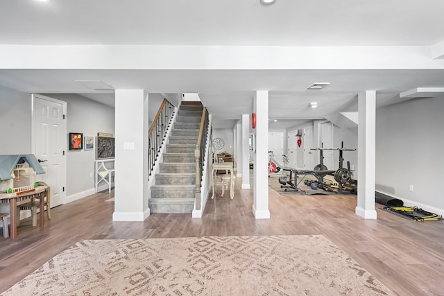 finished below grade area with baseboards, stairs, wood finished floors, and visible vents