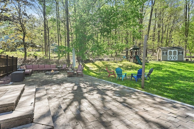 deck with an outdoor living space with a fire pit, a playground, a patio area, a storage shed, and a yard