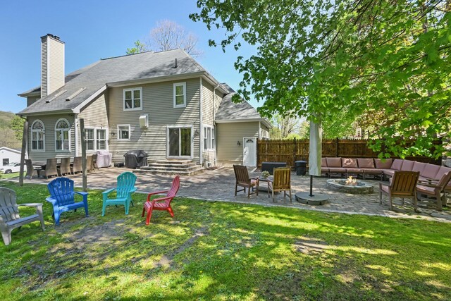 rear view of property with a lawn, an outdoor living space with a fire pit, a patio, and entry steps