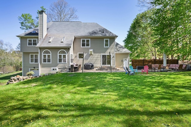 back of house with an outdoor living space with a fire pit, a patio, a chimney, entry steps, and a yard