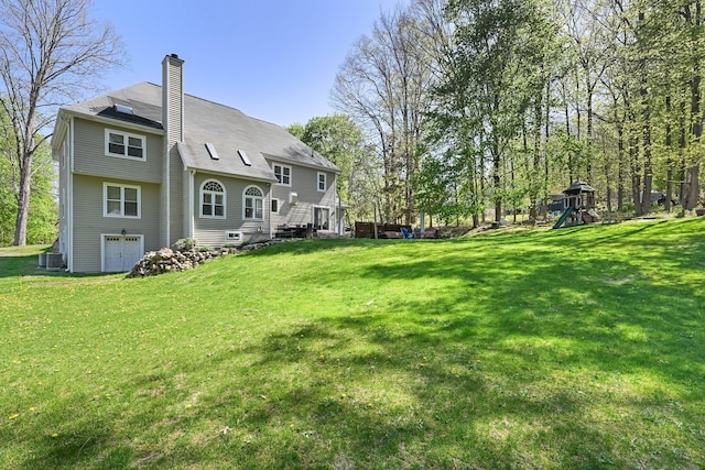 back of house with a yard, a chimney, and a playground