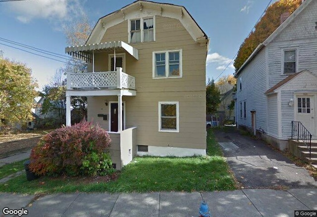 view of front facade with a gambrel roof and a balcony