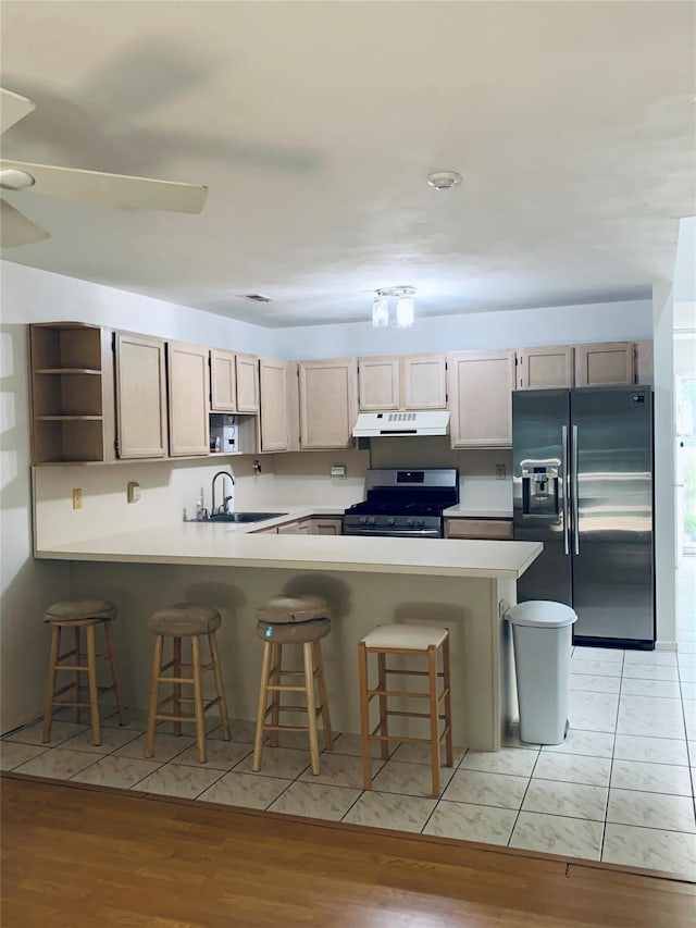 kitchen featuring open shelves, a sink, stainless steel appliances, under cabinet range hood, and a peninsula