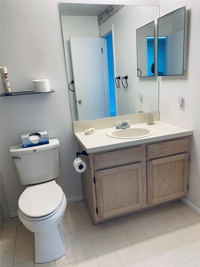 half bath with baseboards, toilet, tile patterned flooring, and vanity