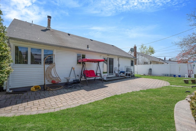 rear view of house featuring fence, a shingled roof, a yard, and a patio area