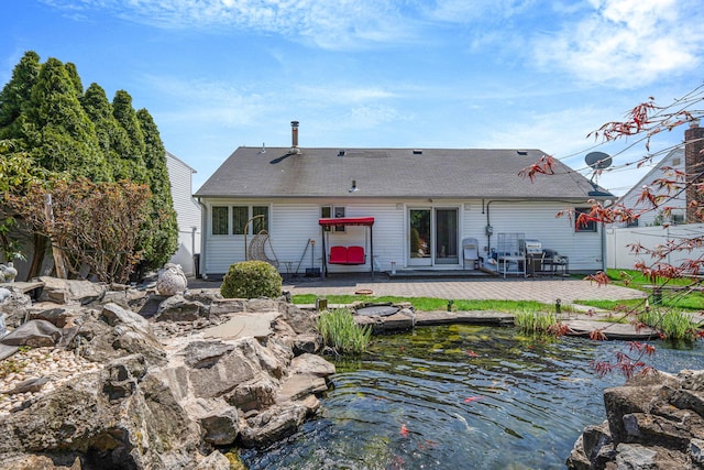 back of house featuring fence, roof with shingles, and a patio area