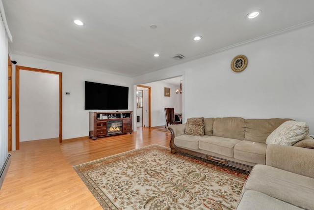 living room with wood finished floors, visible vents, recessed lighting, and ornamental molding