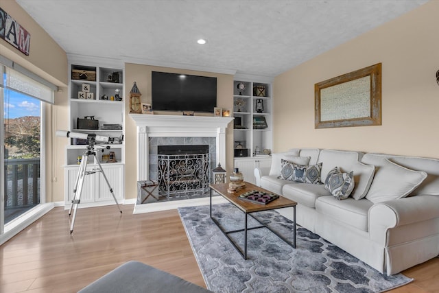 living area featuring recessed lighting, built in features, wood finished floors, and a tile fireplace