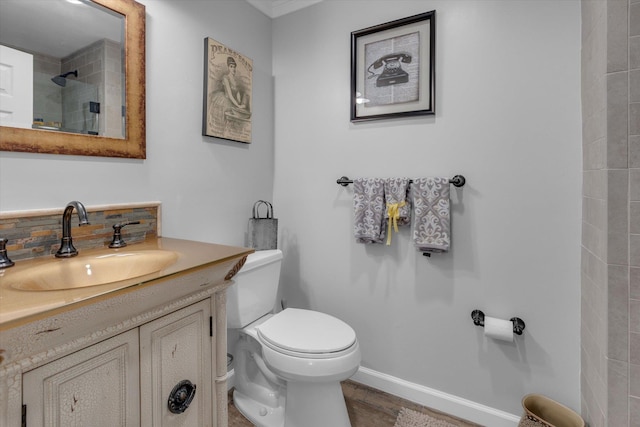 full bath with a tile shower, vanity, toilet, baseboards, and wood finished floors