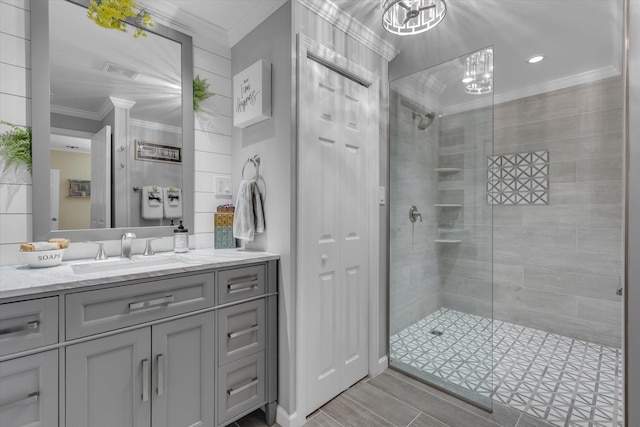 bathroom with crown molding, visible vents, a tile shower, and vanity
