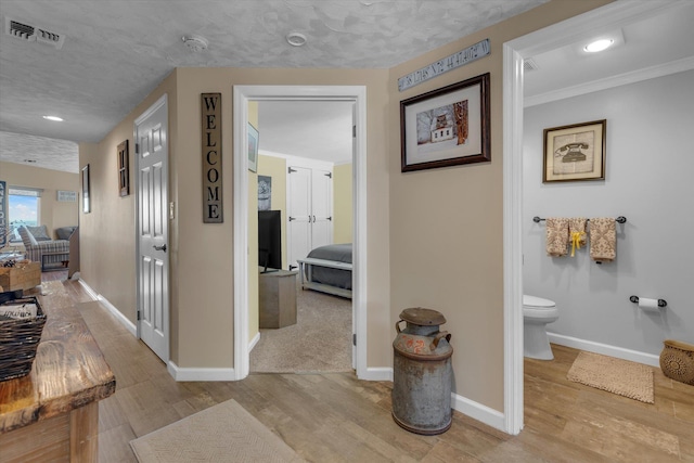 hallway featuring baseboards, visible vents, and wood finished floors