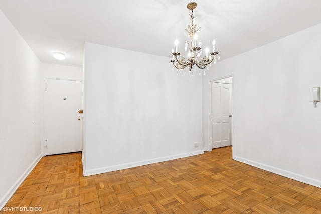 spare room featuring a chandelier and baseboards