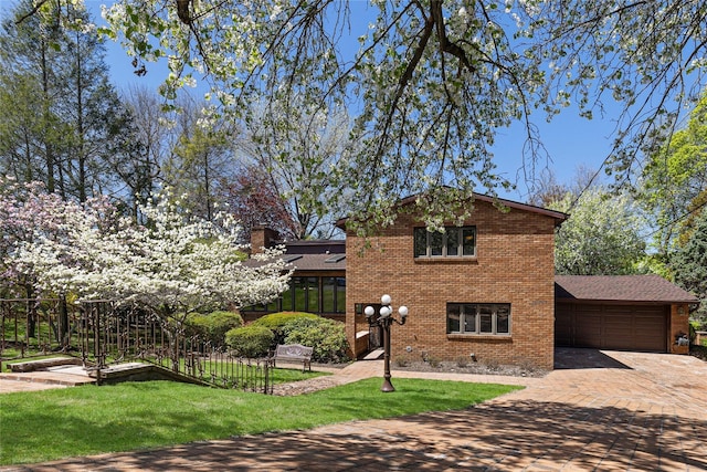 traditional-style home with a chimney, brick siding, decorative driveway, a front lawn, and an attached garage