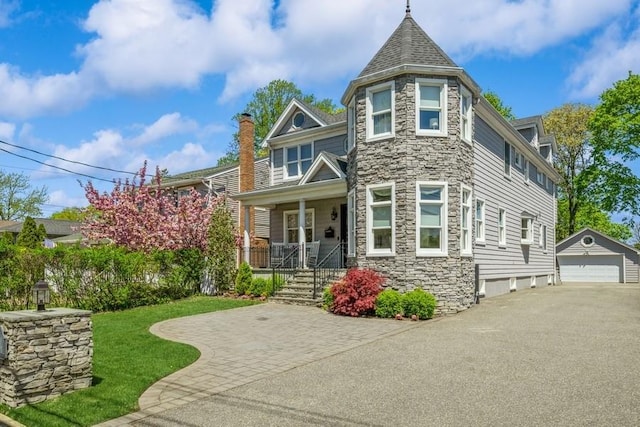 187 Lakeview Ave, Rockville Centre, NY 11570 - view of front facade with stone siding, covered porch, an outbuilding, a detached garage, and a front lawn