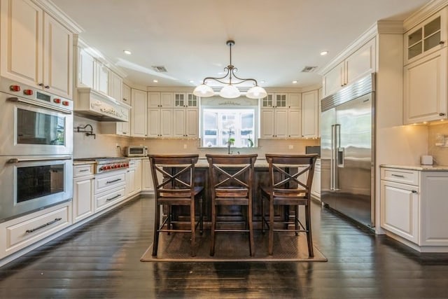 187 Lakeview Ave, Rockville Centre, NY 11570 - kitchen featuring stainless steel appliances, dark wood-style floors, recessed lighting, glass insert cabinets, and a kitchen bar