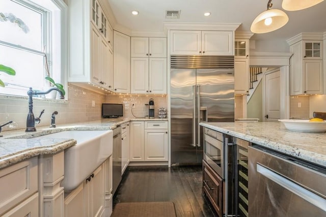 187 Lakeview Ave, Rockville Centre, NY 11570 - kitchen with built in appliances, dark wood-type flooring, glass insert cabinets, light stone counters, and tasteful backsplash