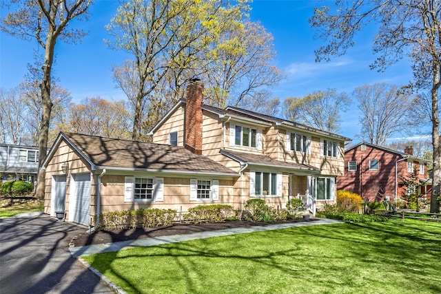 view of front of home featuring driveway, a chimney, a shingled roof, a front yard, and an attached garage